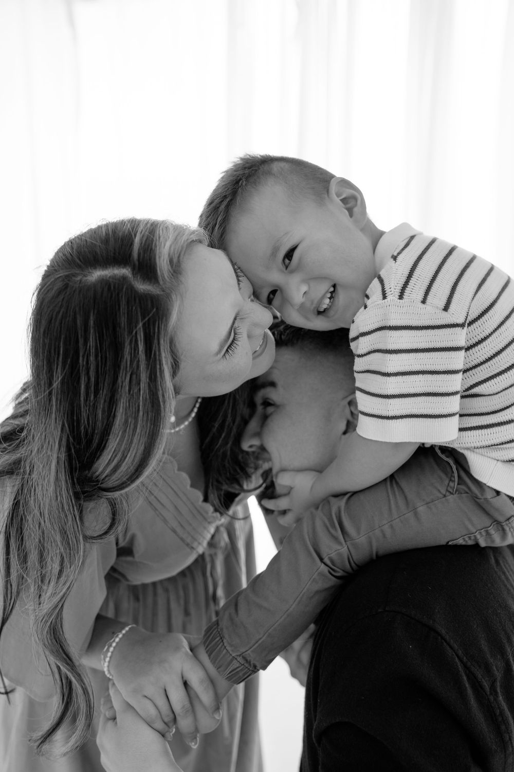 A series of black and white intimate family portraits showing playful interactions and tender moments.