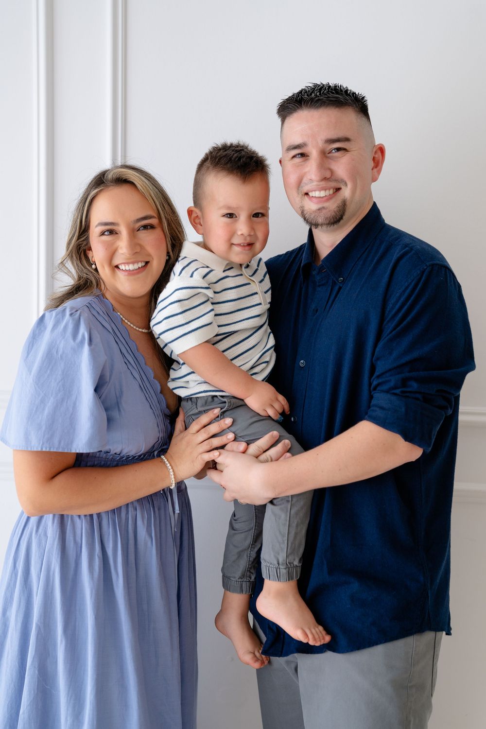 A family wearing coordinated blue and white outfits poses together against a light background.