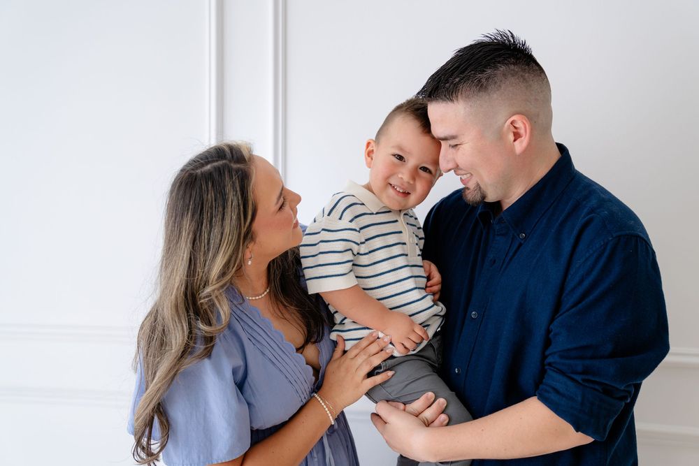 A family shares a joyful moment together against a white background, smiling and embracing.