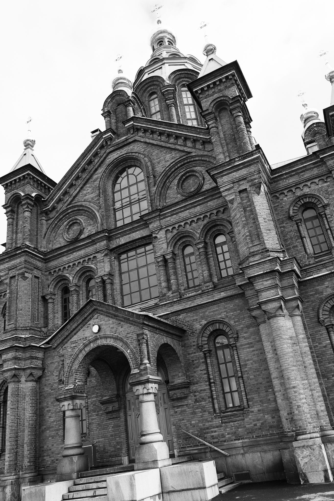 Black and white photo of grand Russian Orthodox brick cathedral with ornate domes and arched windows in Helsinki.