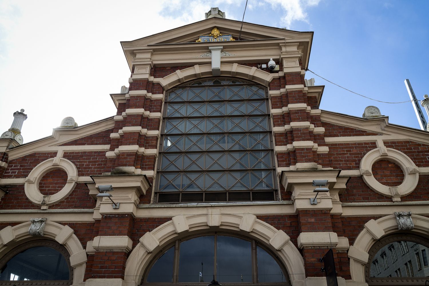 Historic red brick market hall building facade with ornate arched window and decorative stonework.