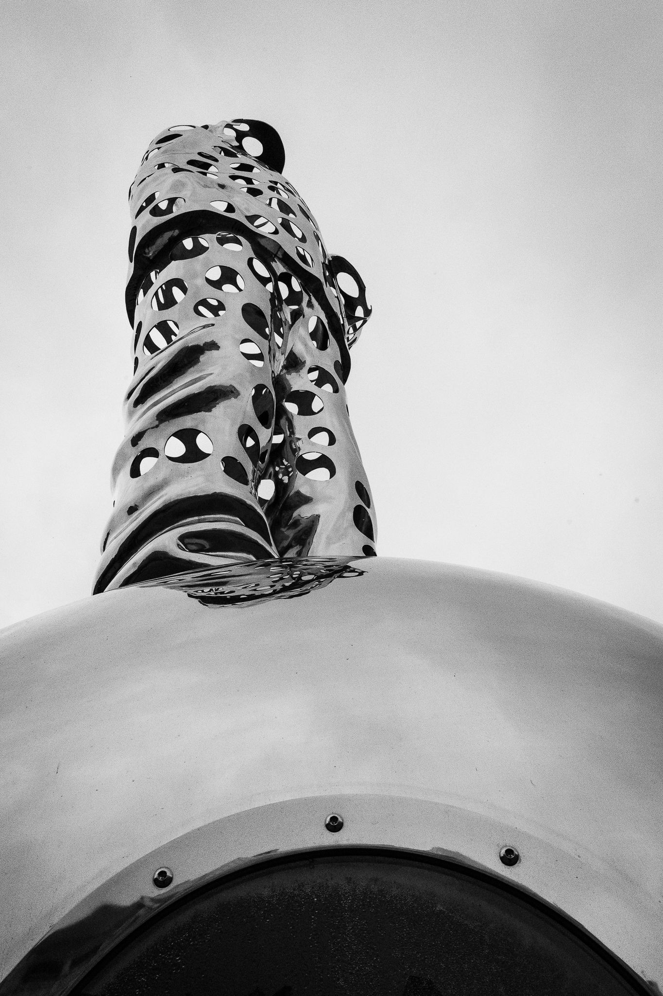 Black and white close-up of abstract polka dot patterned metallic sculpture on reflective sphere.