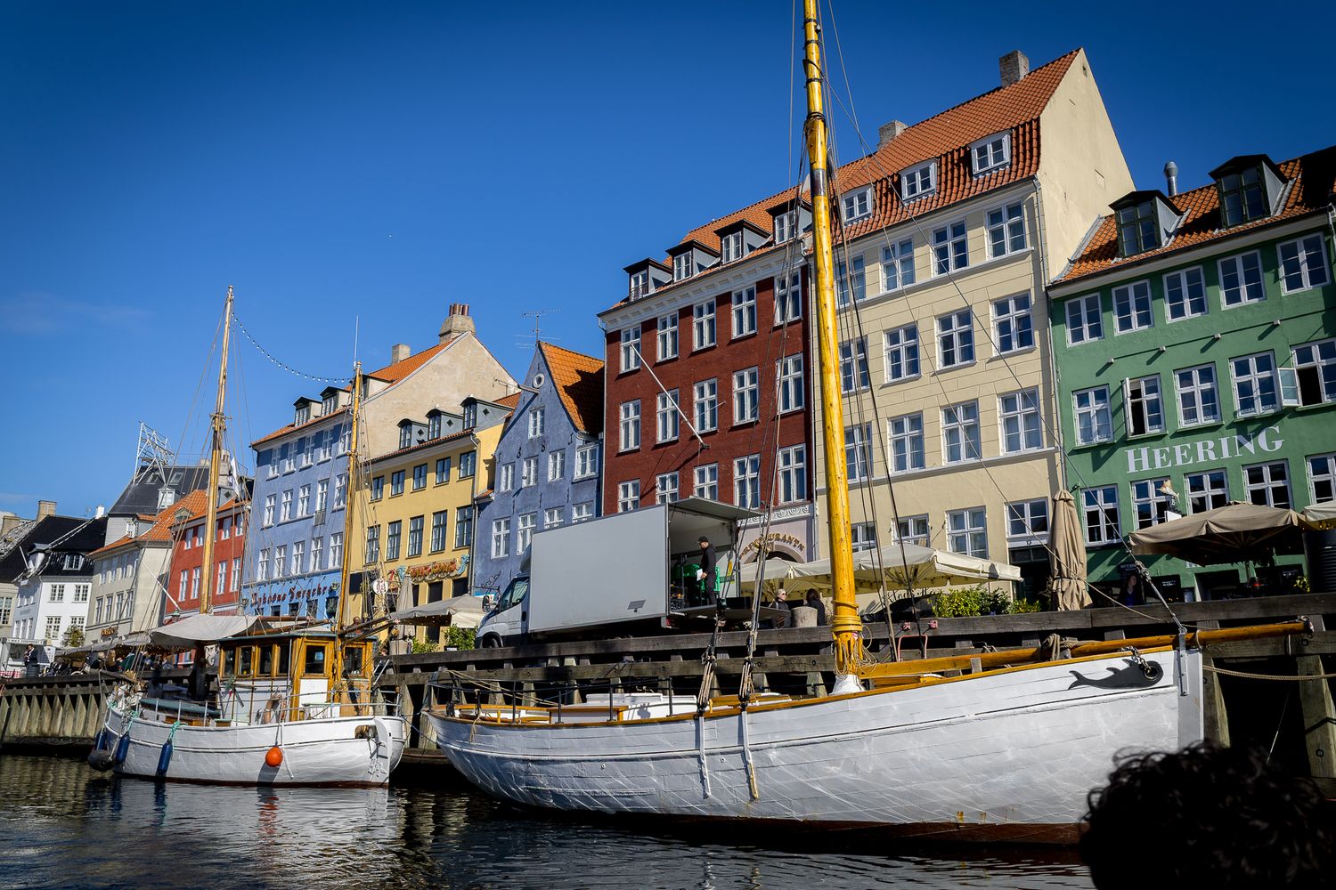 Classic white sailing vessel docked at Copenhagen's Nyhavn canal lined with colorful 17th-century townhouses.