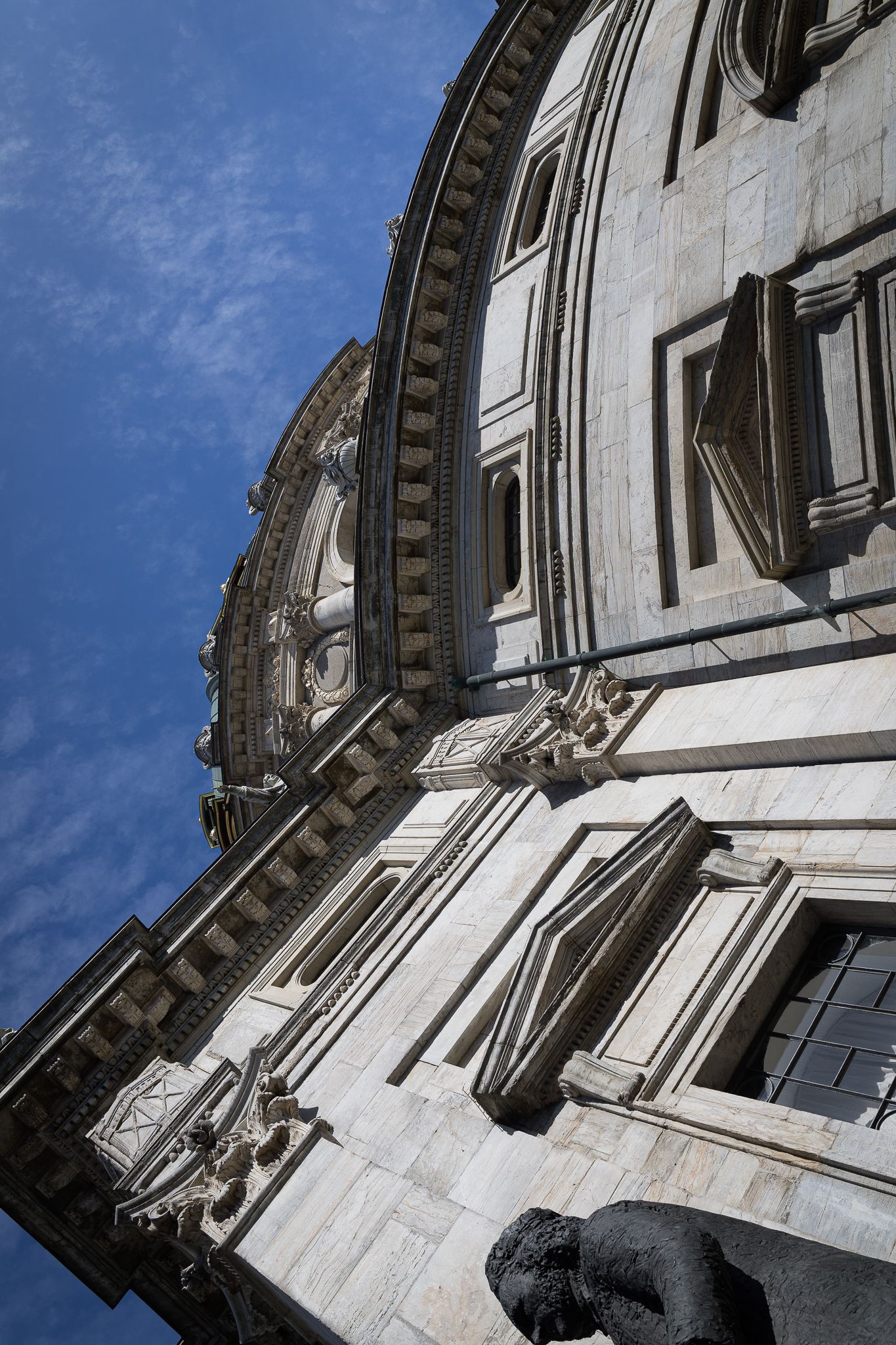 Low angle view of an ornate marble cathedral exterior with decorative carvings against a blue sky.