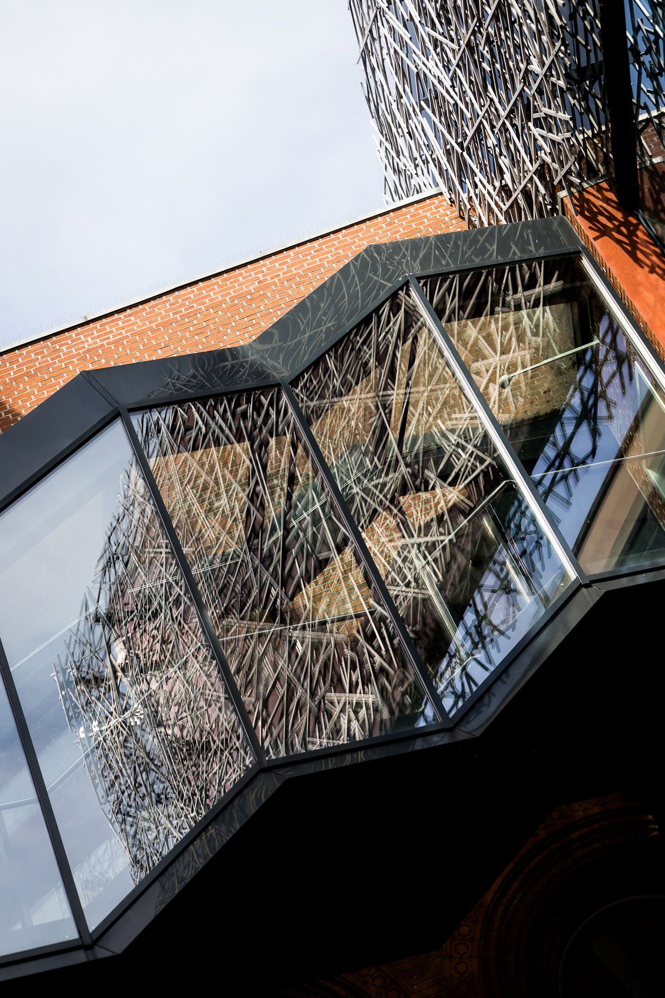 Modern angular glass facade with intricate branch-like interior installation on a contemporary building.