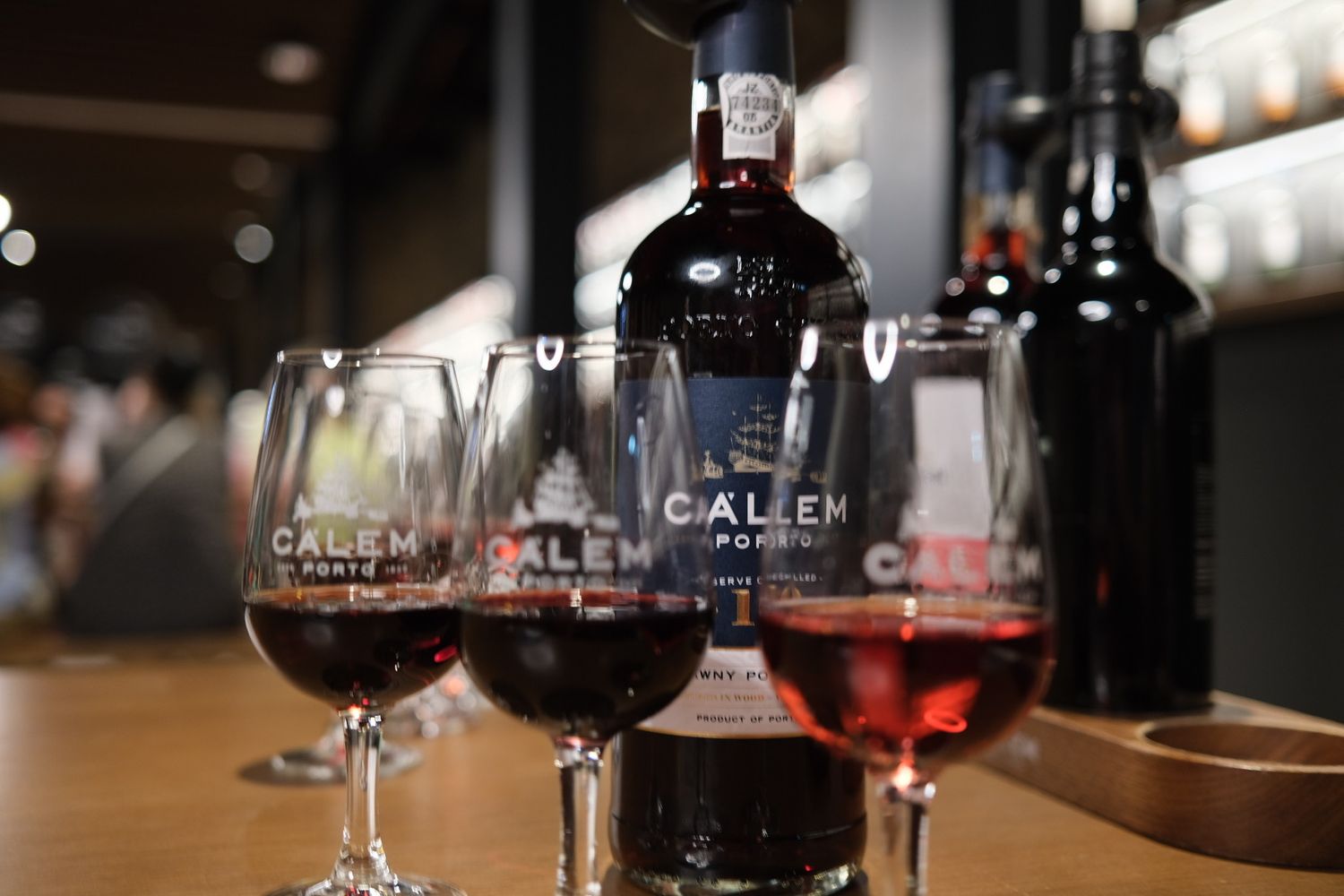 Calem Porto wine tasting with two glasses of red port wine and a bottle on a bar.