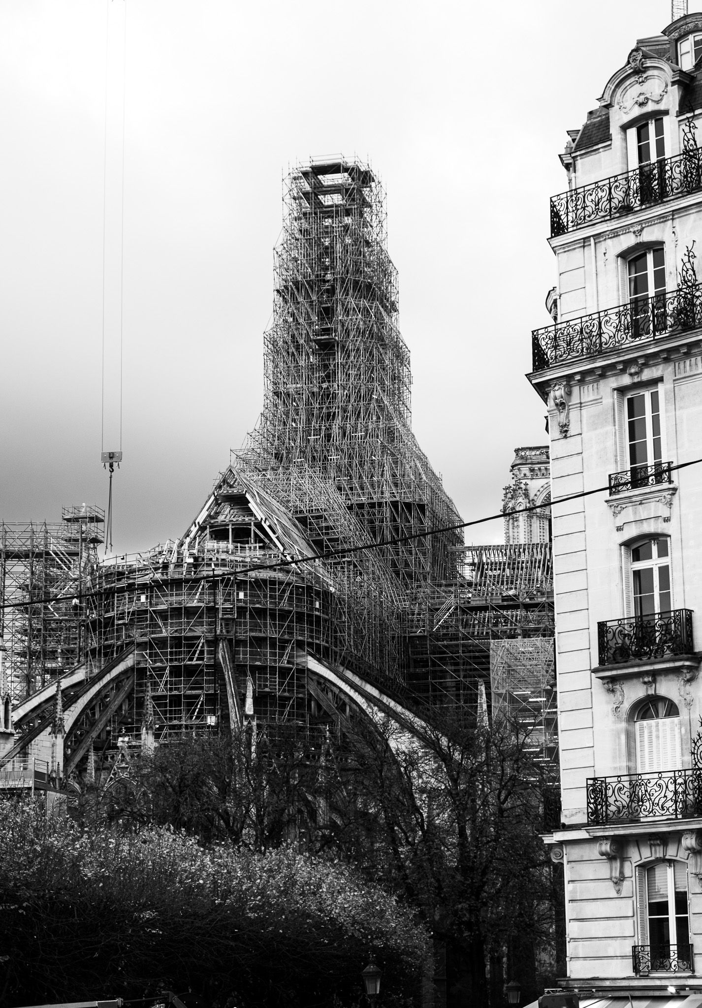 Black and white photo of Notre-Dame Cathedral under reconstruction with scaffolding in Paris.