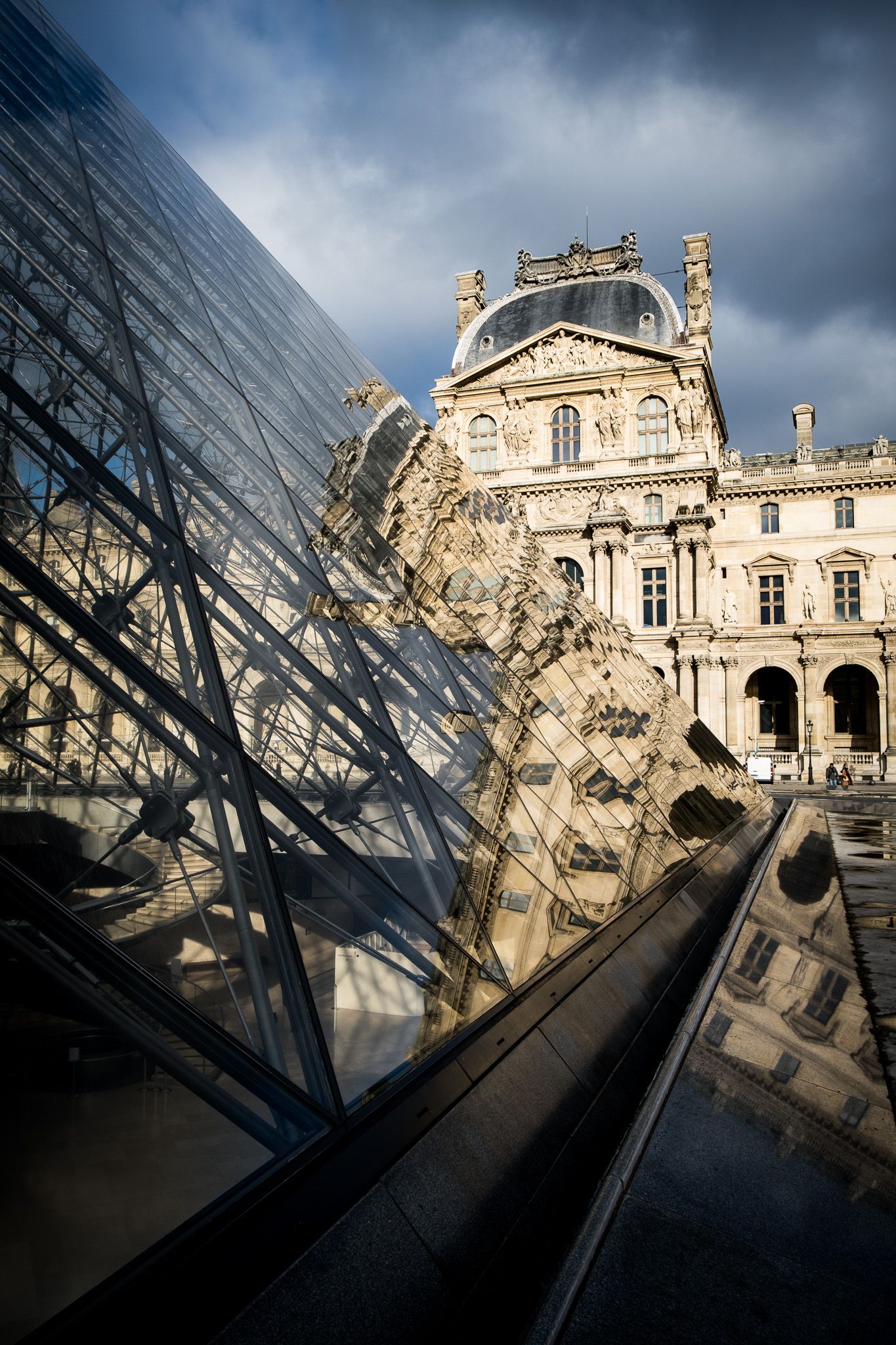 The iconic glass pyramid of the Louvre Museum reflects the historic Richelieu wing facade in Paris, France.