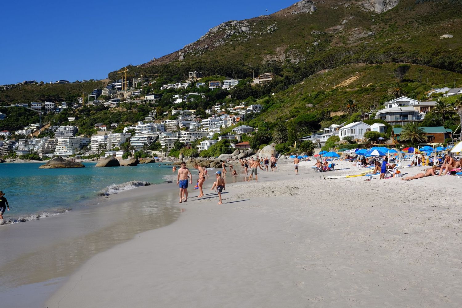 Tourists enjoy a sunny day on the white sandy beach at Clifton Beach, Cape Town, South Africa.