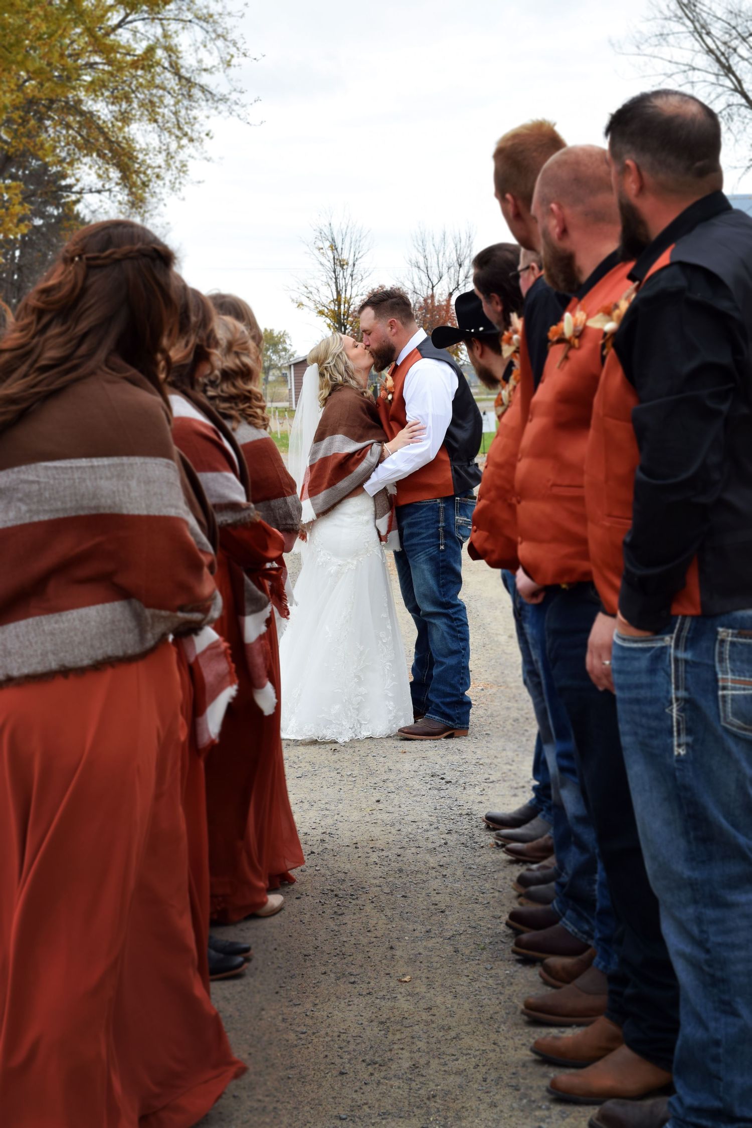 Wedding party lineup in rustic outdoor setting with people wearing brown and denim.