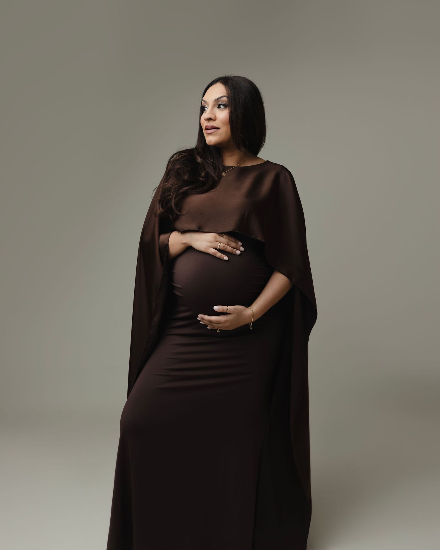 A maternity photoshoot sequence featuring a woman in a flowing brown dress against a light gray background. Elizabeth Lang Photography Surre