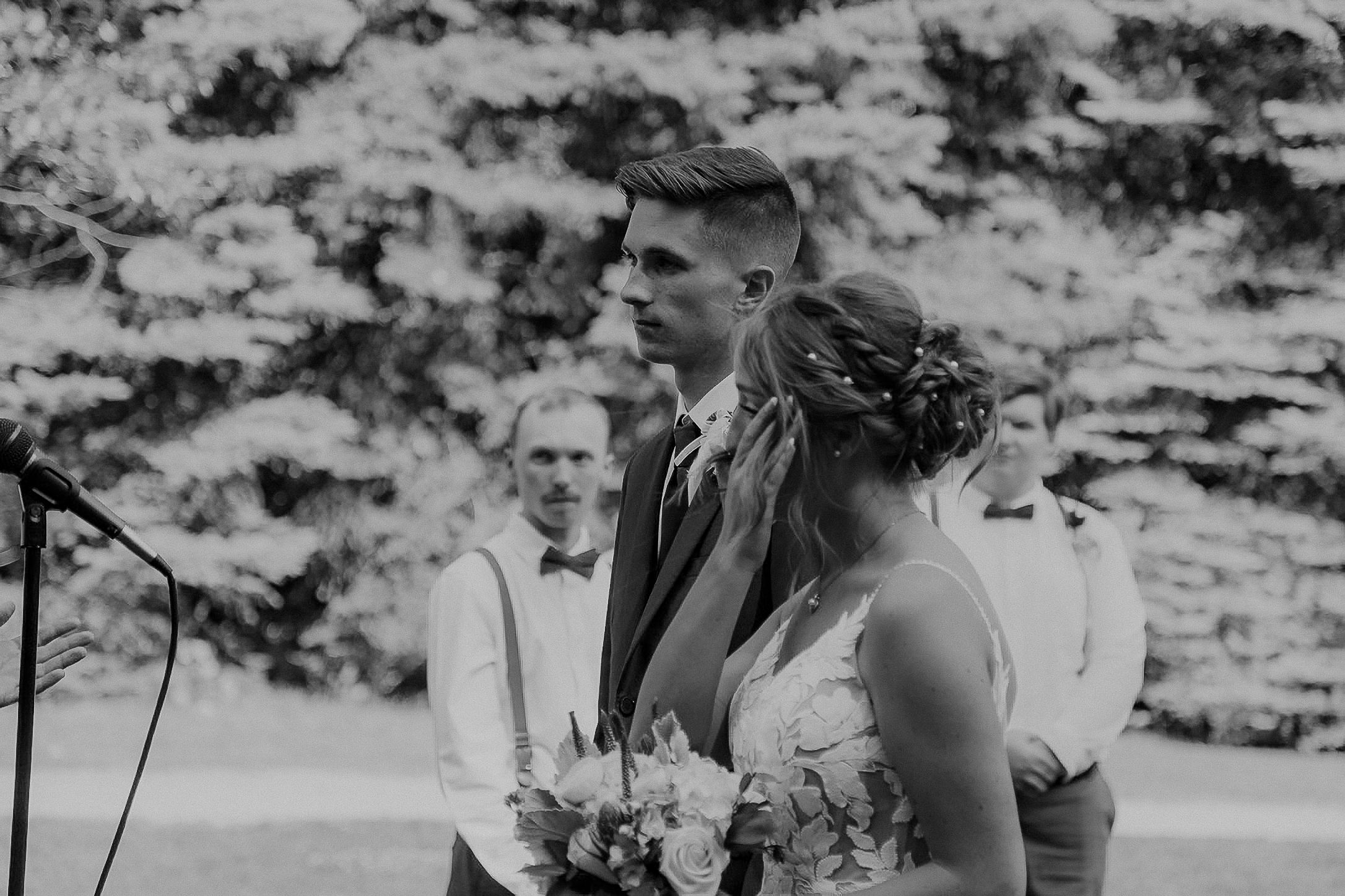 Black and white wedding photographs showing intimate embraces and candid moments between newlyweds in a natural setting.