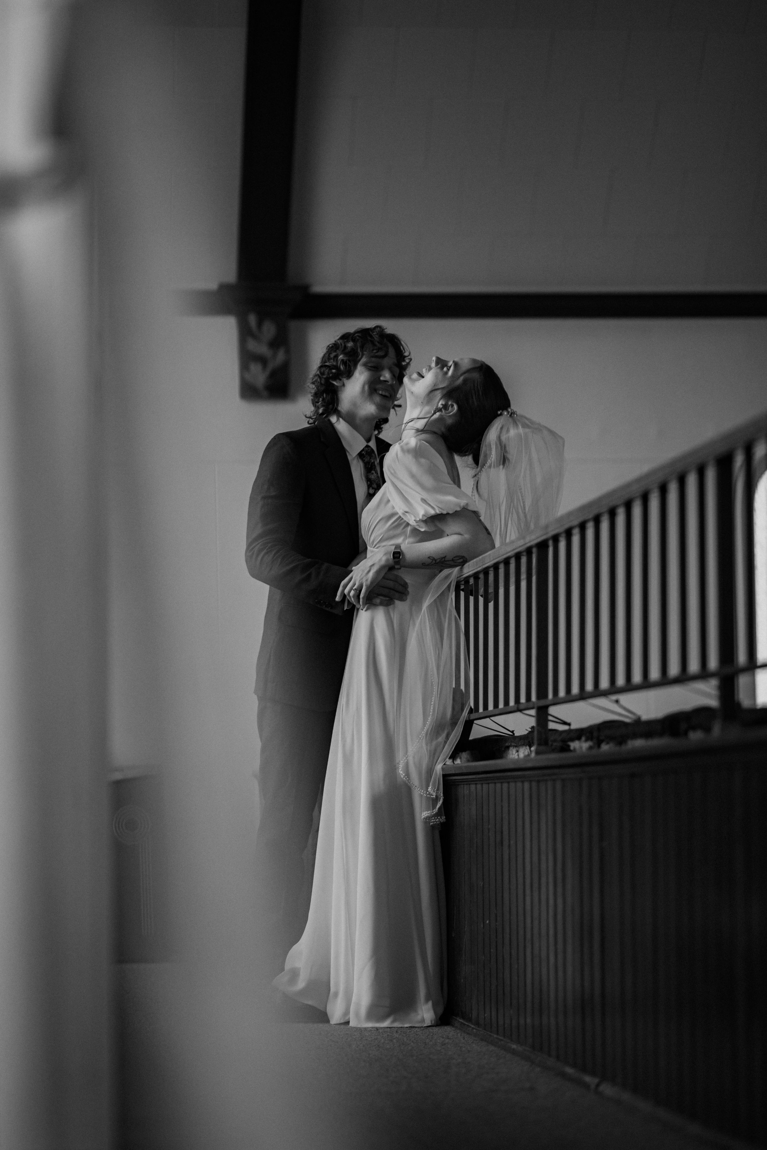 A tender black and white wedding moment captured on a staircase as a couple shares an intimate embrace.