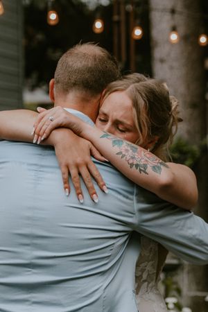 Close-up shots of a couple embracing with string lights glowing in the background, showing arm with visible tattoo.