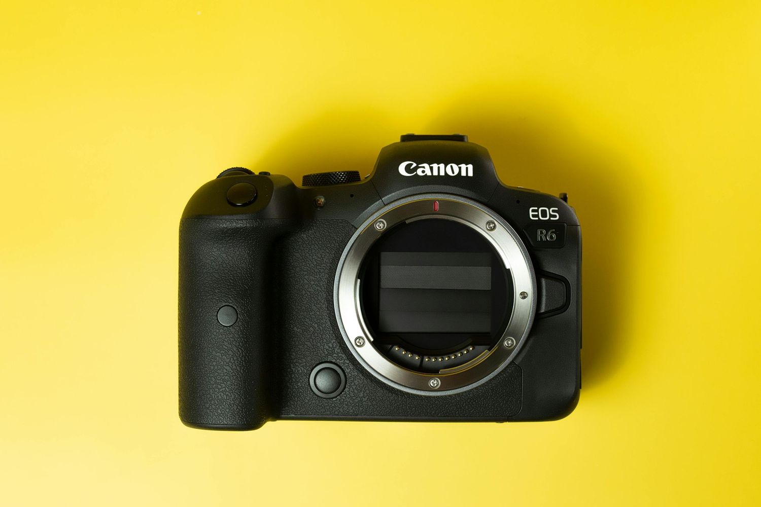 Canon EOS R6 mirrorless camera body without lens on a bright yellow background.