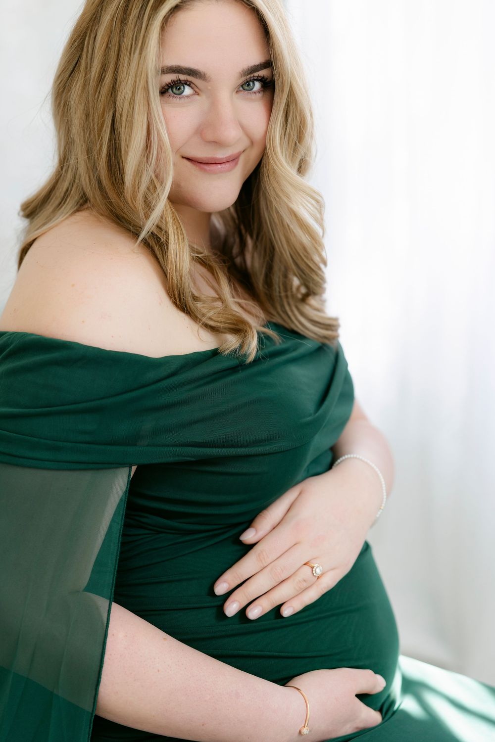A series of maternity photos showing a woman in a dark green dress against a white background.