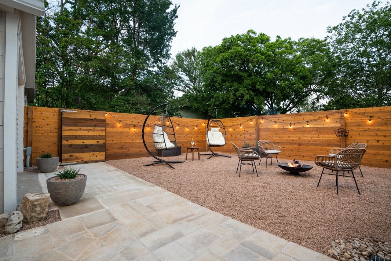 Panoramic view of a backyard patio space with wooden privacy fence and outdoor furniture.