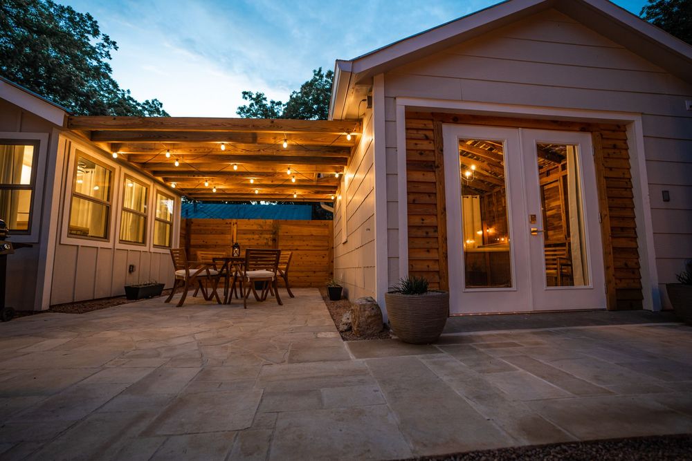 Covered outdoor patio with warm lighting by Fusion Master Builders