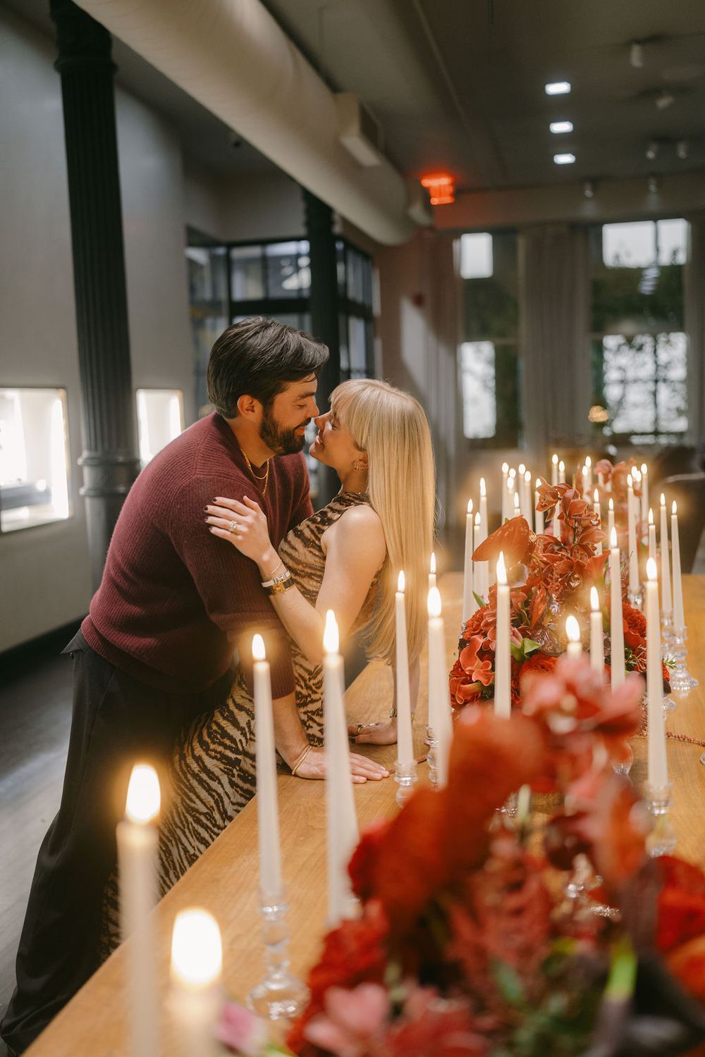 A romantic candlelit scene with flowers and glowing candles decorating a long table.
