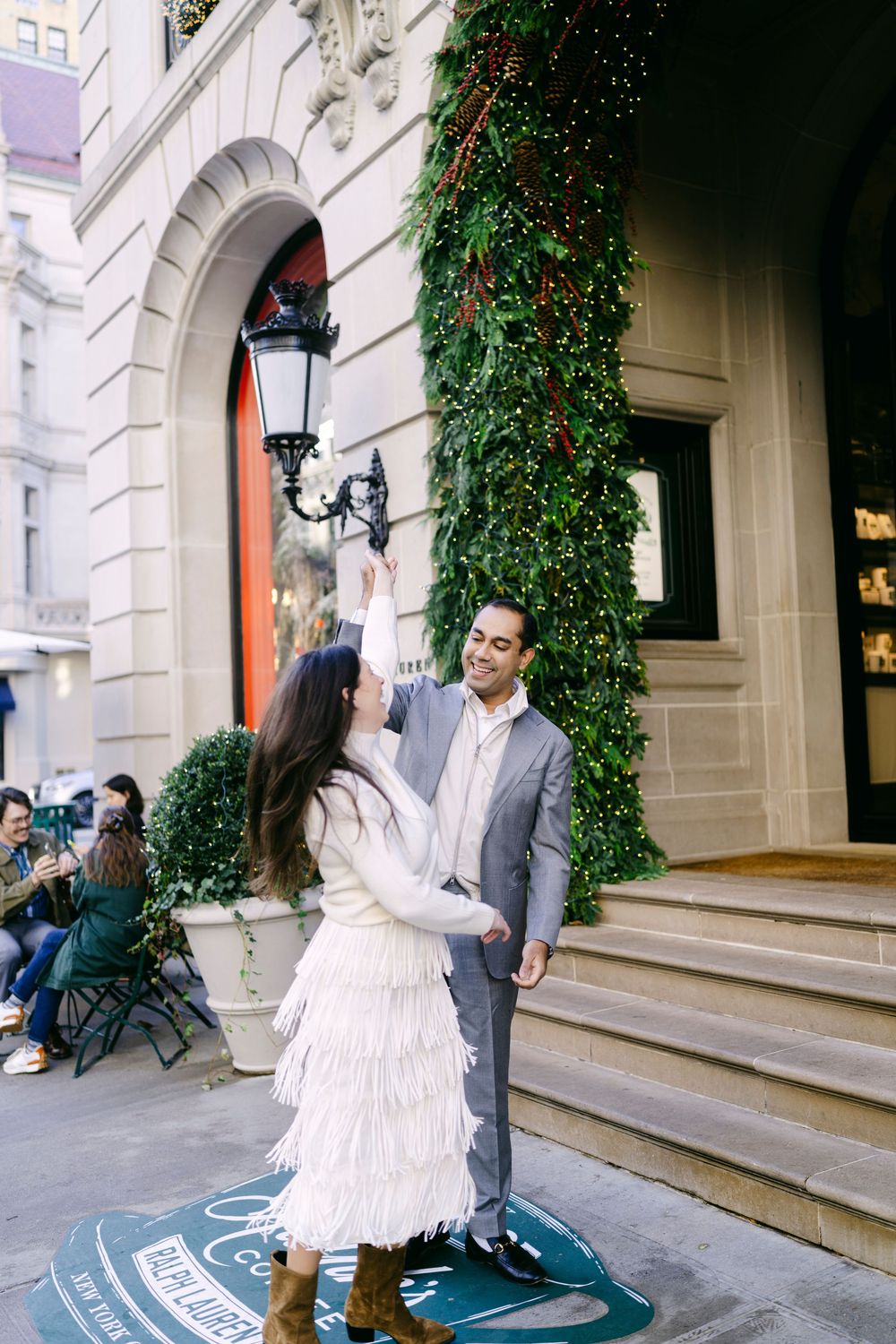 A couple in formal attire shares a romantic moment on stone steps with ivy-covered walls behind them.