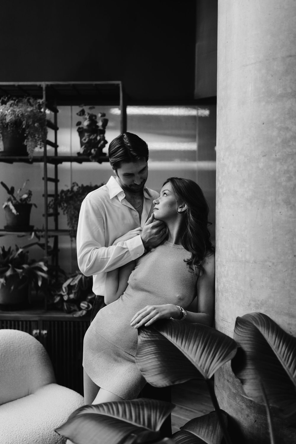 A romantic black and white photo series showing tender moments between a couple on a couch with pillars in the background.