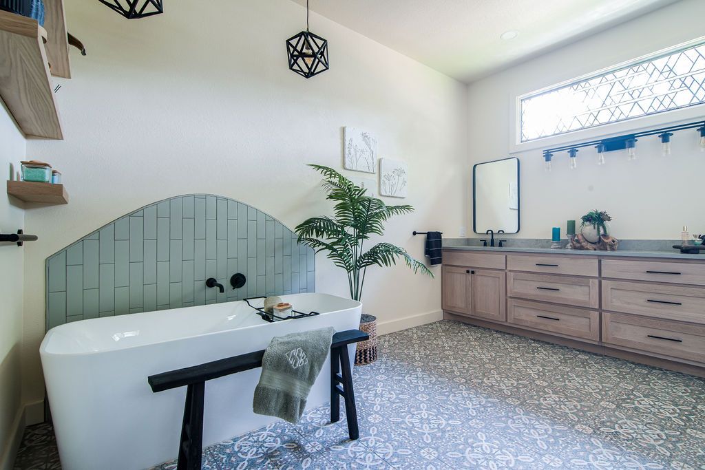 Master bathroom remodel featuring a freestanding soaking tub and sage green vertical tile accent wall.
