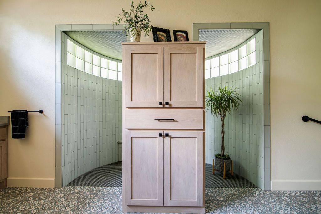 Elegant bathroom storage cabinet positioned between curved tile walls with minimal decor.