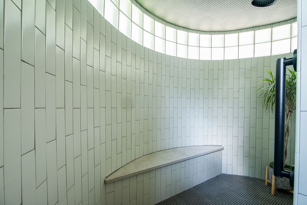 Unique architectural bathroom design with curved white tile walls and integrated bench seating in Kerrville.