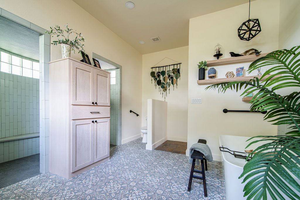 Modern bathroom entryway with light wood cabinet, terrazzo flooring, and botanical decor elements.