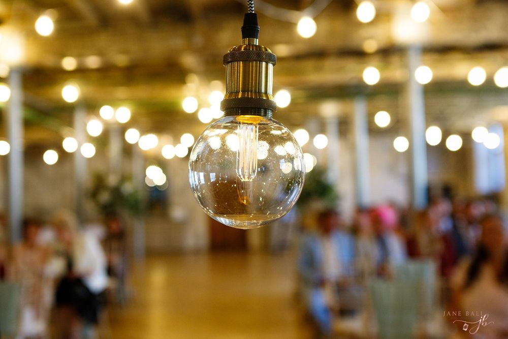 Warm string lights illuminate an elegant indoor wedding venue with a romantic glow.