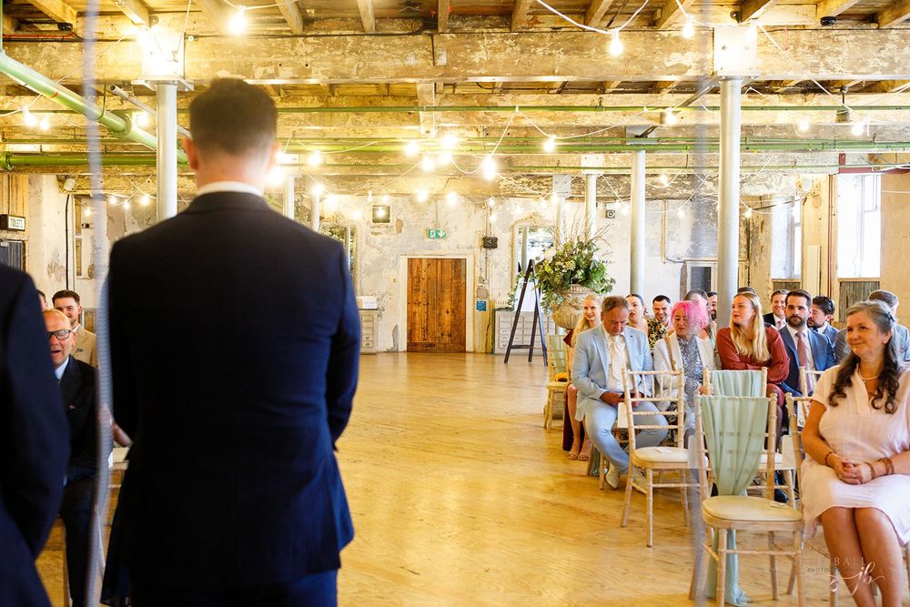 Spacious industrial-style wedding venue with exposed beams and natural lighting.