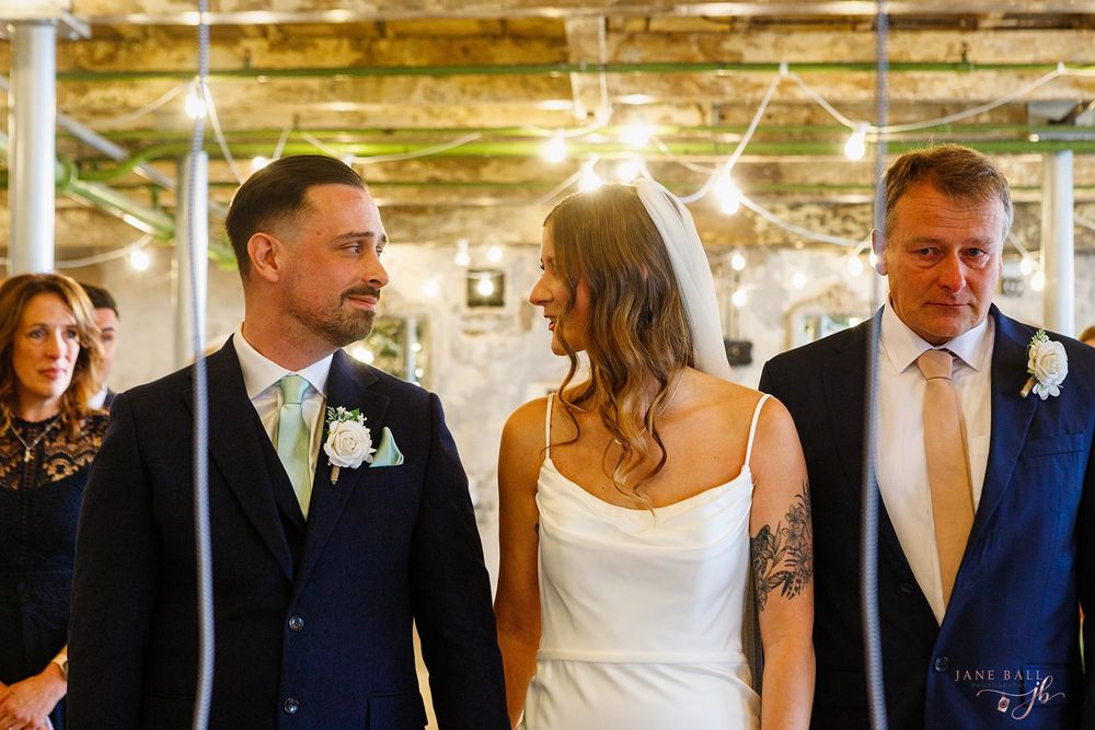 Wedding party walks together in a row through a beautifully lit indoor venue during a celebration.