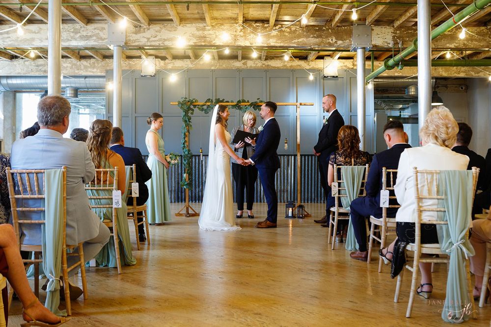 People gather in a modern office space with exposed ceiling beams and large windows for a business event.