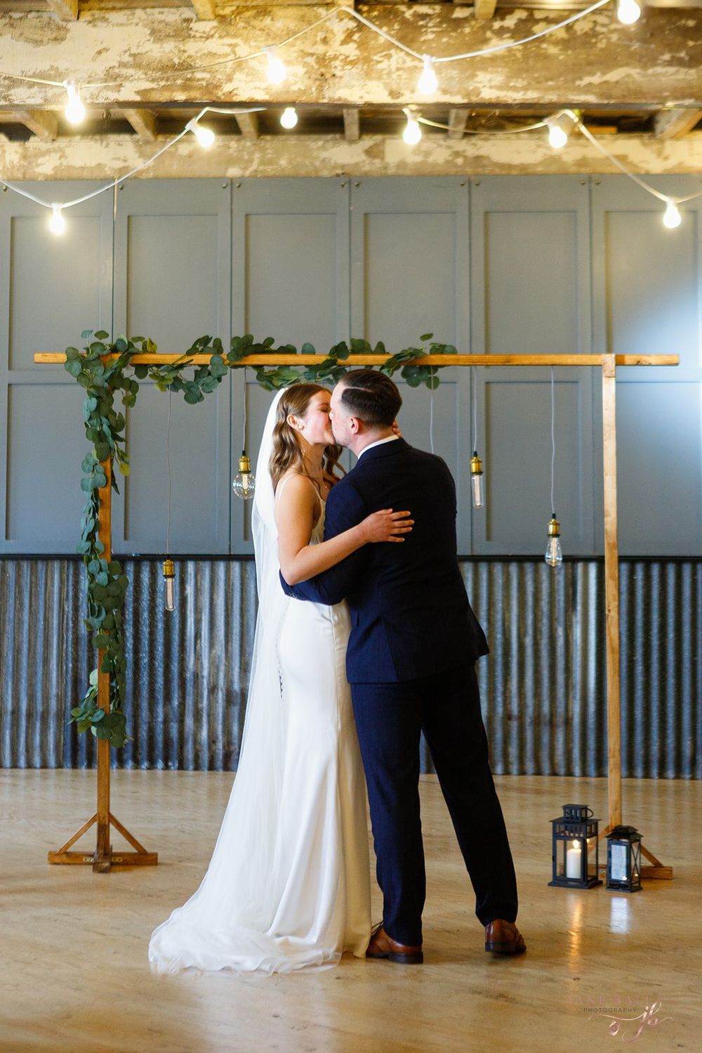 A romantic first dance sequence between newlyweds in a rustic venue with string lights and wooden beams.
