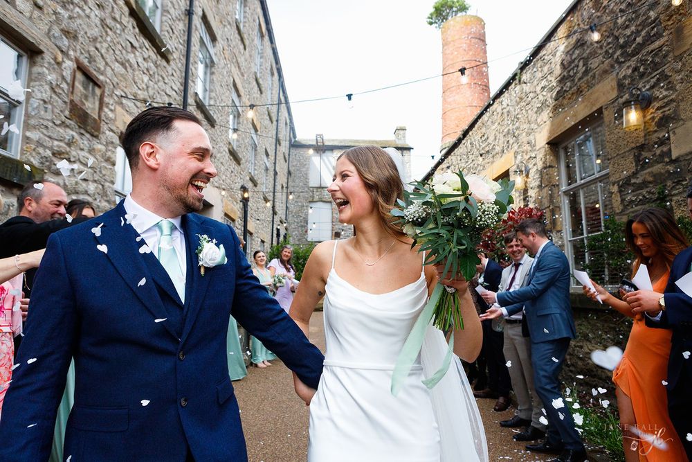 A happy couple shares joyful moments during their wedding celebration in a rustic stone courtyard.