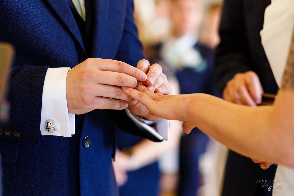 Close-up shot of hands exchanging wedding rings during an elegant ceremony.