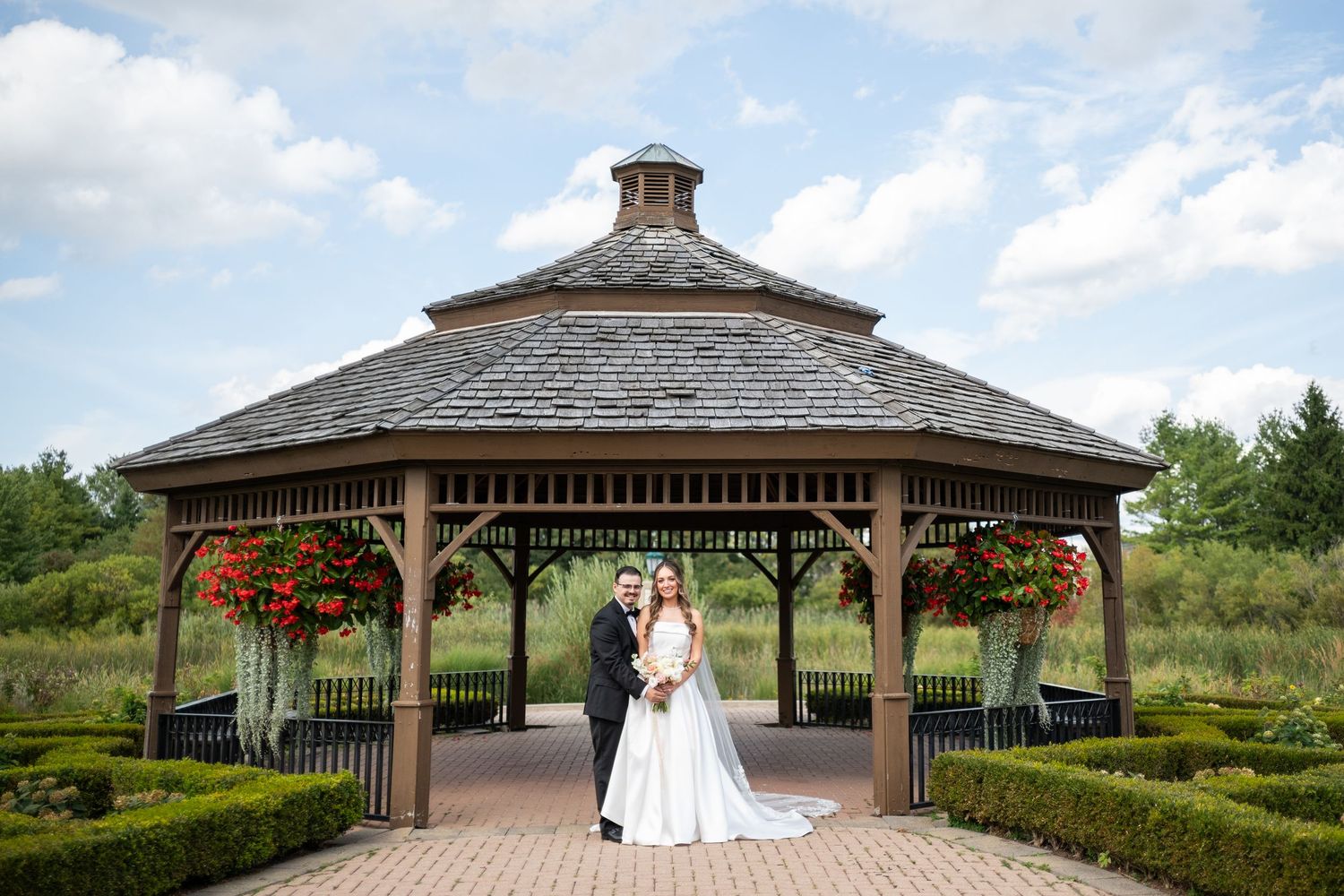 A panoramic view of a wedding venue's outdoor gazebo surrounded by manicured gardens and natural landscape.