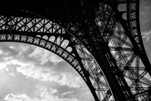 Silhouettes of the Eiffel Tower's iconic arches captured in high contrast black and white.
