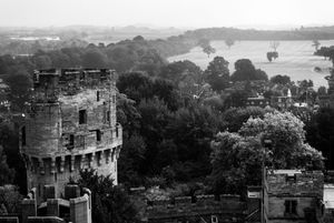 Black and white landscape view of historic castle ruins overlooking a scenic countryside.