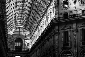 Architectural details of an ornate glass-covered shopping arcade or gallery shown in black and white.