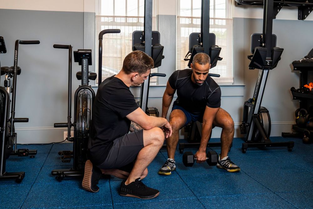 People working out in a modern gym with exercise equipment and weight machines in a panoramic shot.
