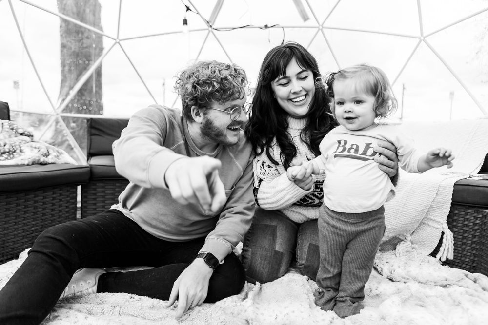 Black and white photo of a happy family relaxing together inside a modern dome structure.