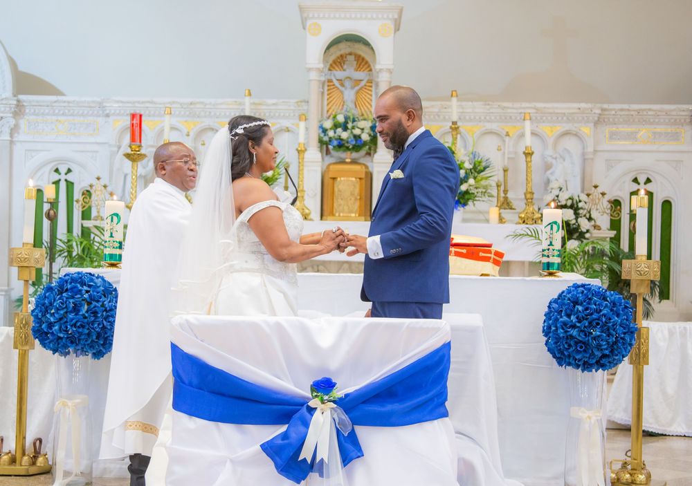 Wedding ceremony in a church with a couple exchanging vows, decorated with blue and white floral arrangements.