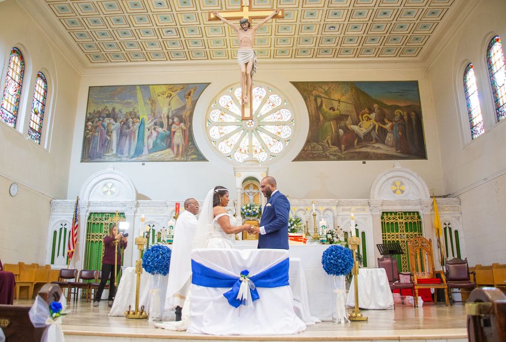 Interior panoramic view of a church sanctuary with ornate ceiling, stained glass windows and chairs decorated with blue bows.