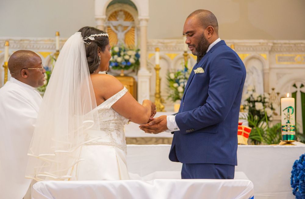 A couple exchanges vows during their wedding ceremony at the altar of an ornate church sanctuary.