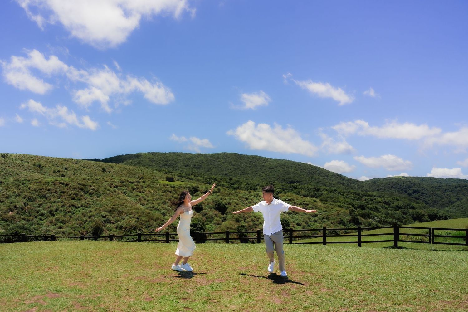A series of panoramic images showing two people photographing a scenic green mountainous landscape on a sunny day.