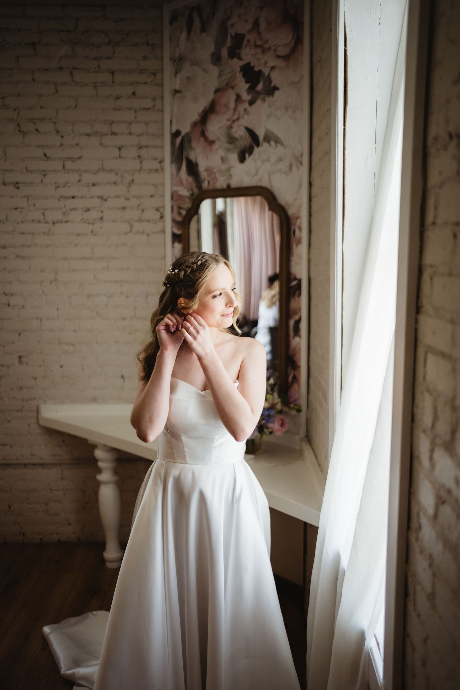 Light streams through windows in an elegant white room with exposed brick walls creating soft artistic portraits.