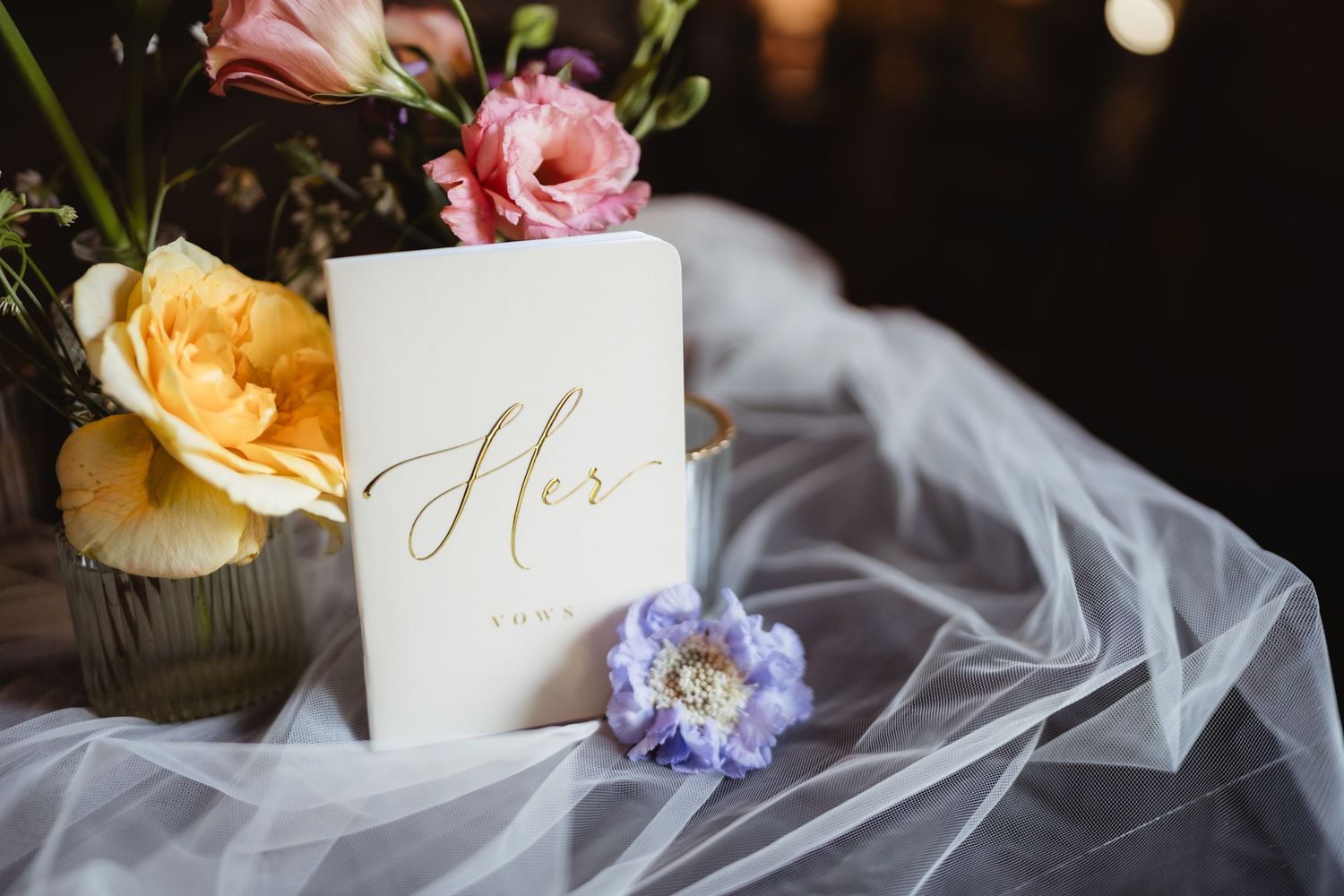 A white wedding card marked 'Hers' with pink and yellow roses on delicate tulle veil fabric.