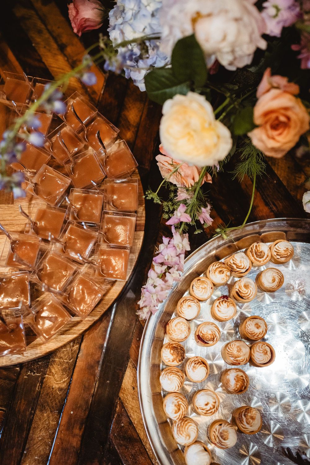 Elegant wedding dessert table with chocolate biscuit roses arranged on silver platters and delicate floral decorations.