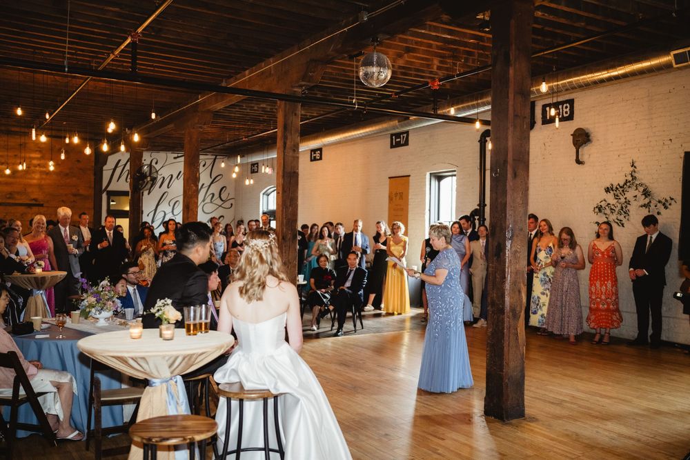 A rustic indoor wedding venue with exposed wooden beams, decorative string lights, and a spacious reception area.